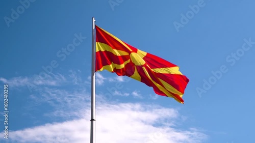 The red and yellow flag of North Macedonia against a deep blue sky; video take in Skopje