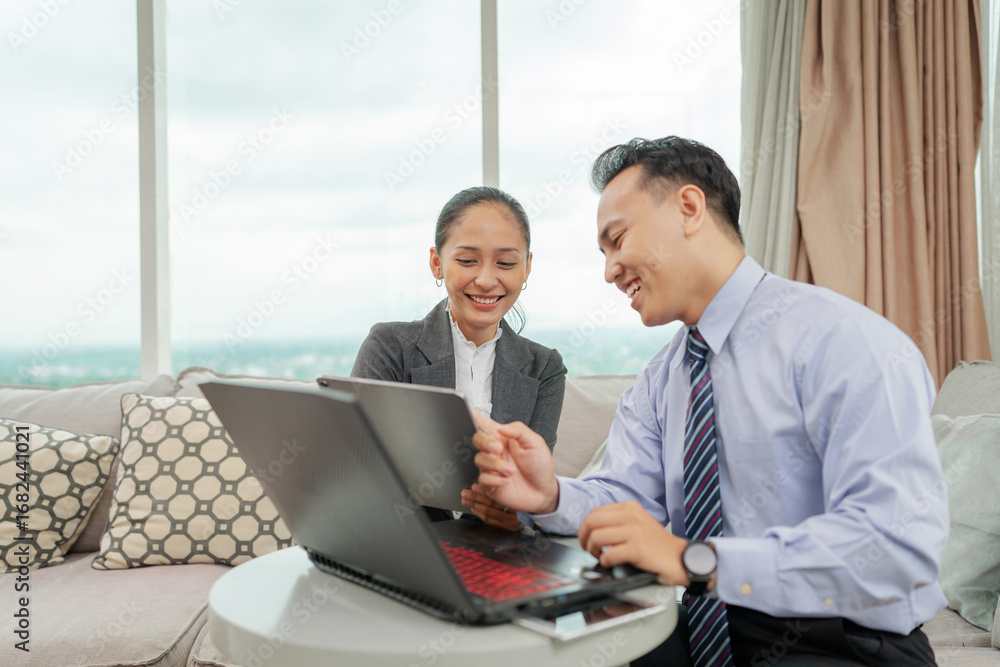 Fototapeta premium Professional duo discussing project strategies over a laptop in an office setting.