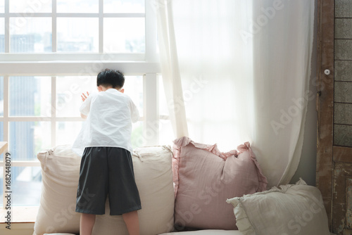 The boy looks outside the window, watching the world go by.