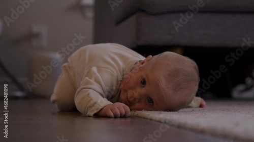 Infant boy with eczema rubs body on floor and carpet to itch - wide shot