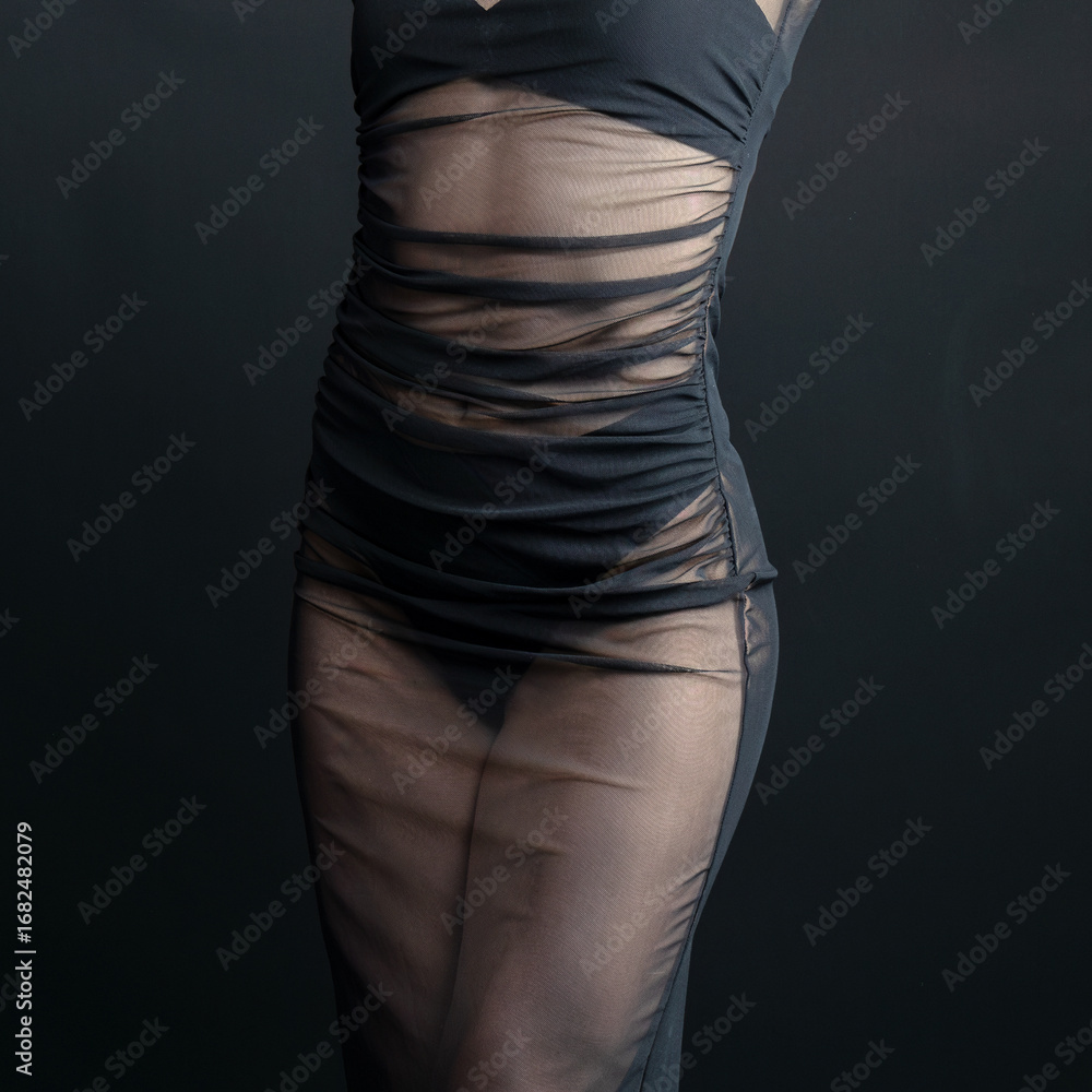 Fototapeta premium Studio shot of a fashion model posing in a transparent black dress against a dark background 