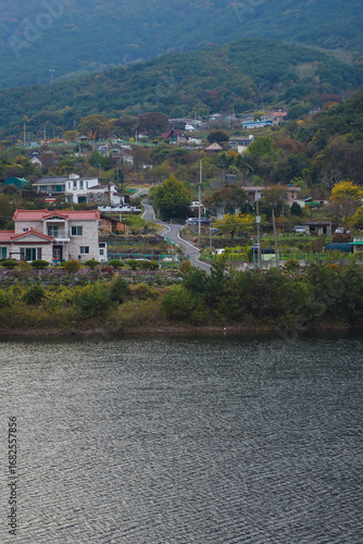 Behind the clear lake, mountains and rural villages are visible.