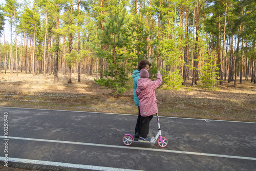Wallpaper Mural Little girl riding scooter while walking with her grandmother in the forest on a sunny day Torontodigital.ca