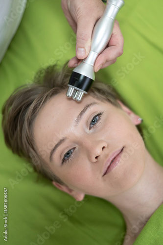 Top view of Caucasian woman undergoing radio wave RF lifting procedure in beauty salon. 