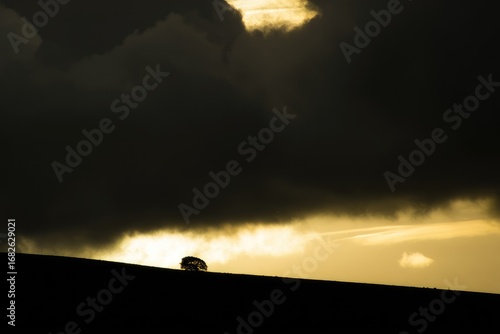 Silhouetted vehicle on a hill, dramatic sunset sky