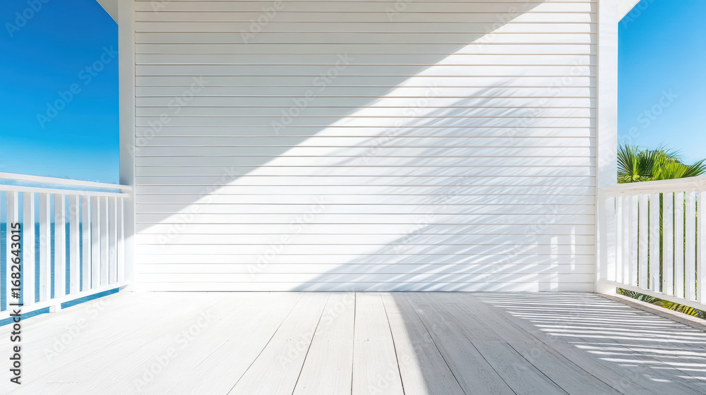 Fototapeta premium Bright white building facade with architectural shadows and clear blue sky creates serene