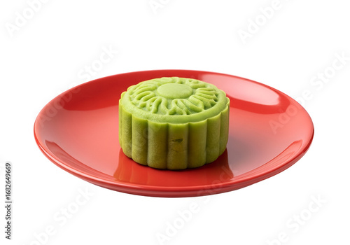 A vibrant green mooncake rests attractively on a polished red plate against a black backdrop, showcasing a delightful dessert.