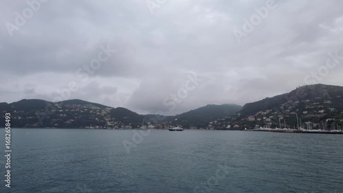 Drone footage captures the tranquil waters of Mandelieu La Napoule surrounded by lush hills and a hazy sky. This scene highlights the coastal village's Mediterranean charm in the South of France.