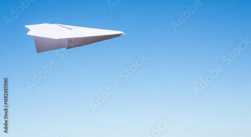 A simple white paper airplane soaring gracefully across a vast, clear blue sky, symbolizing freedom, travel, and dreams