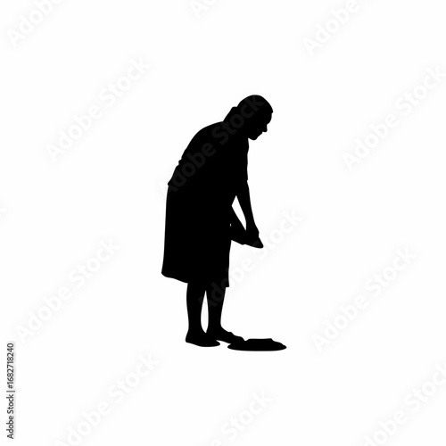 Silhouette of a woman creating a colorful rangoli at her doorstep