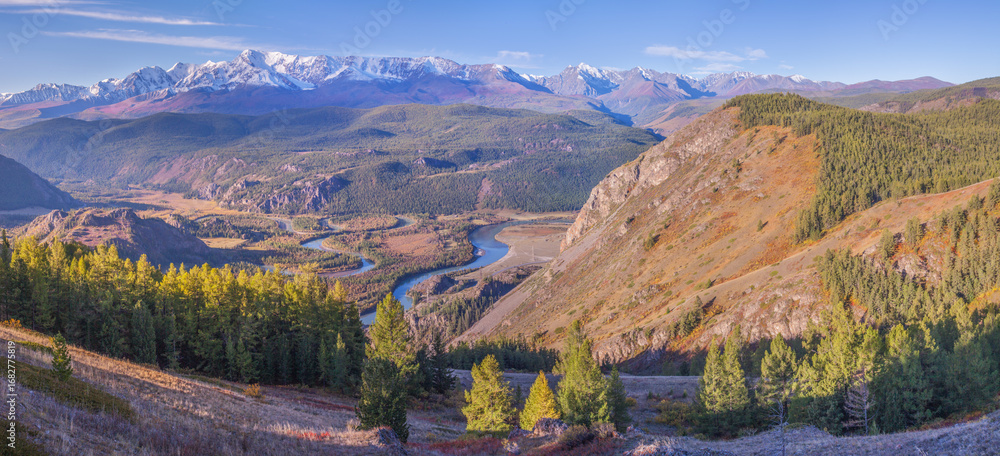 Naklejka premium Mountain autumn landscape, river meanders in the valley, snow-capped peaks 