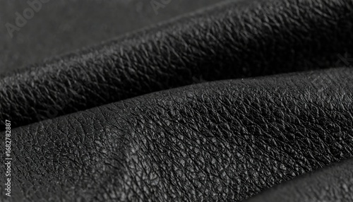 Textured black material features layered folds, offering a close-up view of the surface's intricate patterns and shadows, creating depth and visual interest