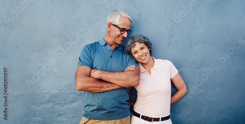 Tableau sur toile Happy senior couple standing together against blue wall