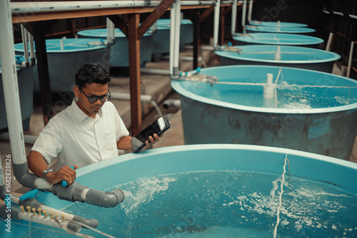 Tableau sur toile Fish Hatchery Pond with Worker Monitoring Aquaculture Tanks