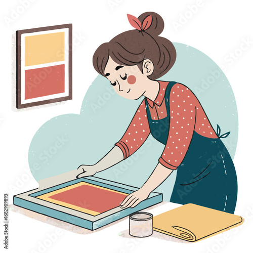 A young woman artist engaged in the screen printing process in her workshop.