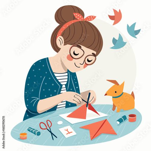A young woman with glasses enjoys her hobby of making origami figures at a table.