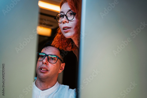 Two developers collaborating while looking at a computer screen. Teamwork in coding, problem-solving, and learning technology skills for business, innovation, and digital transformation projects.