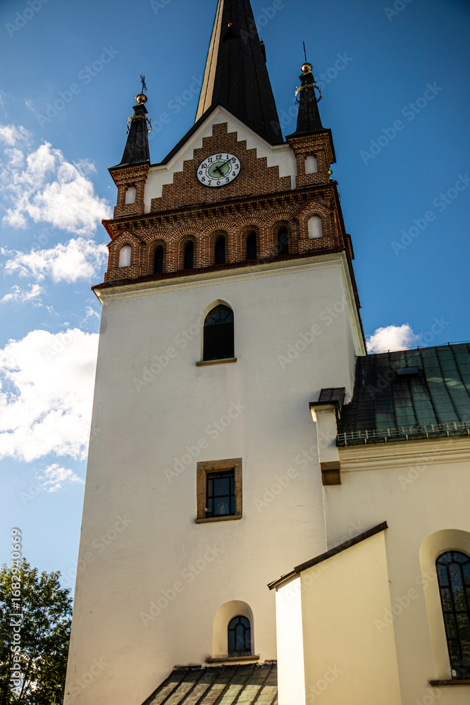 Fototapeta premium A tall church tower with a clock and a dark spire