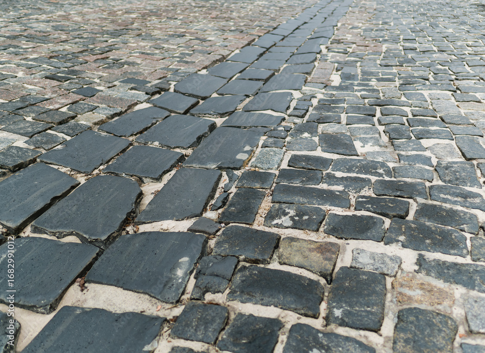 Fototapeta premium A road paved with large cobblestones, close-up. Background