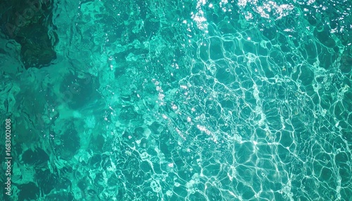 Shimmering turquoise sea water with sun reflections. Clear, cool water ripples and shines with bright, scattered sun patterns. Overhead view