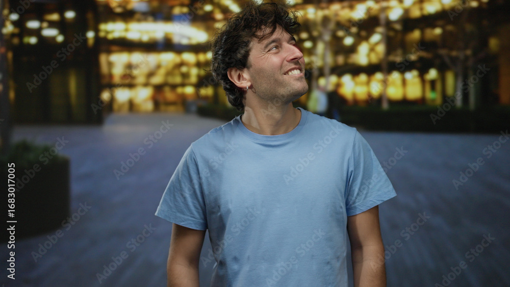 Hispanic man smiling outdoors in a bright urban area with a blurred background of lights showcasing a lively street setting at night Hispanic man smiling outdoors in a bright urban area with a blurred background of lights showcasing a lively street setting at night