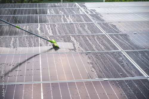 Φωτογραφία Solar worker using mob cleaning dirt and water on solar panels surface on roof