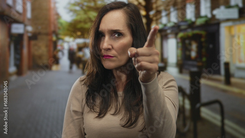 Wallpaper Mural Woman pointing with determination on a bustling city street, capturing the urban vibe with confident expression and casual attire in an outdoor setting with blurred background. Torontodigital.ca