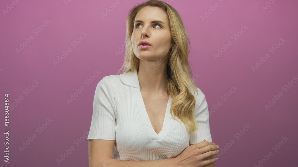 Fototapeta premium Woman thinking and posing against a vibrant pink background, with long blonde hair and casual white attire, conveying emotion and individuality.