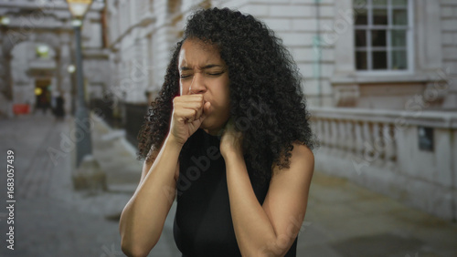 Foto Woman coughing outdoors on an urban street, showing concern for health while casually dressed in a city environment