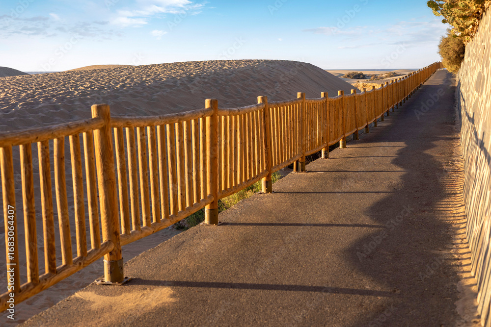 Obraz premium Walking path running along Natural Reserve of Dunes of Maspalomas in Gran Canaria, Canary Islands, Spain.