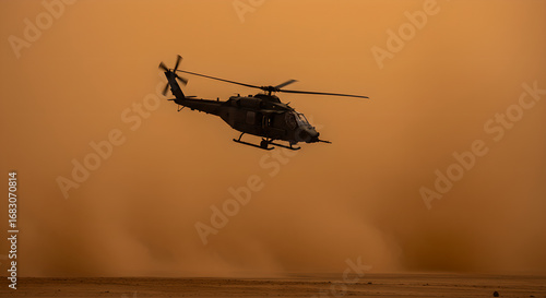 Military helicopter flying above dusty desert landscape during sandstorm. Action shot of military aircraft in flight. For news and articles.