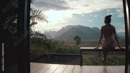Tourist is enjoying a relaxing moment on a terrace, taking in the breathtaking view of lush green mountains in thailand
