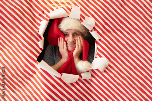 Cheerful person peeking through Christmas wrapping paper