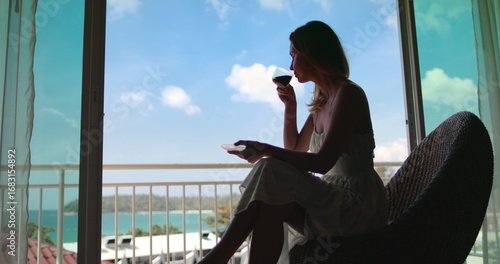 Young elegant woman drink coffee on balcony enjoy ocean view. Female relax in Phuket, Thailand exotic nature. Outdoor lifestyle travel summer holiday vacation on tropical island. Perfect morning