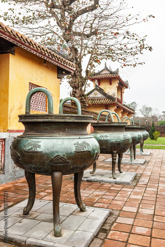 Row of ancient bronze dynastic urns on tiled terrace at Hue Imperial City Vietnam