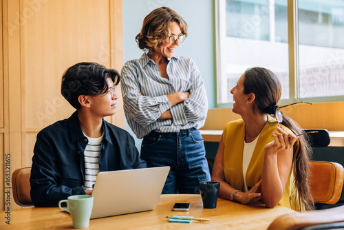 Fotografie Young professionals engage in joyful conversation during a casual office meeting