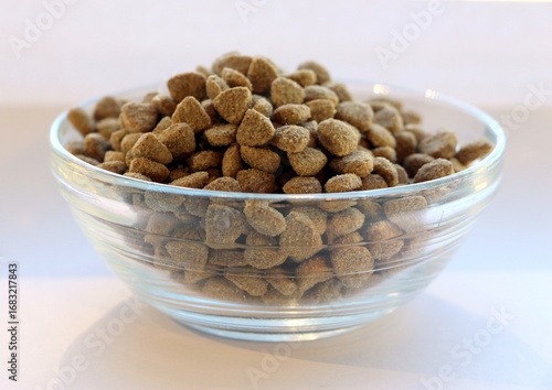 Canvas Print Dry balanced food for cats or dogs in a glass transparent bowl on a white background