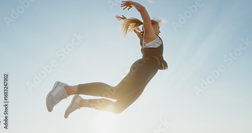 A Dynamic Jumping Woman Exuding Energy Against a Beautifully Clear Sky Above Her