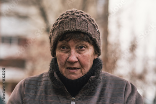 Fotografie Elderly woman reflecting thoughtfully in urban park during a cool afternoon in e