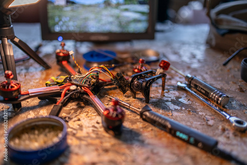 A close-up view of a FPV drone assembly on a workbench, showcasing various tools and components used for building and repairing drones. neutral background, clear negative space, clean composition