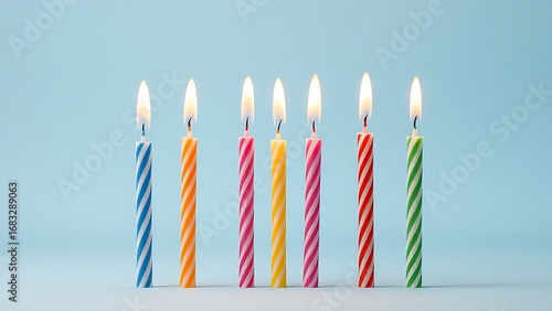 Row of colorful birthday candles with flickering flames, isolated on a soft blue background.