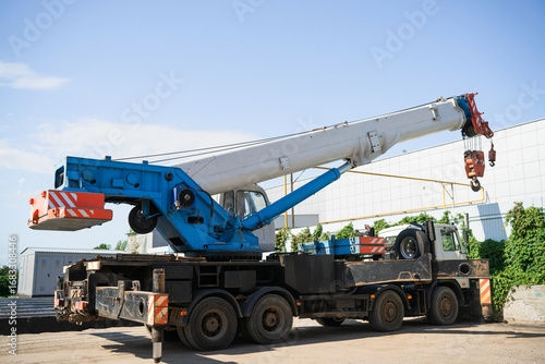 A white and blue truck crane at a construction site is preparing for loading