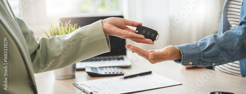 Agent in auto leasing giving key of car to client after all document and paperwork contract signed.