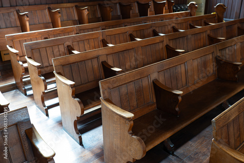 Empty church pews inside protestant church in Europe. Wide angle view, natural window light, no people