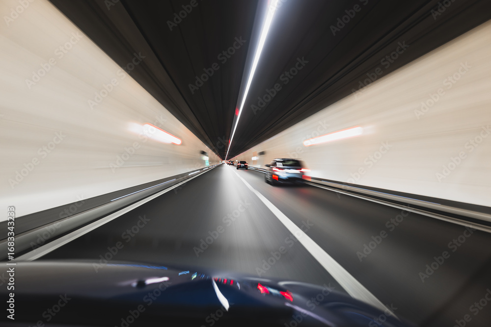 Fototapeta premium Blurry cars driving through a tunnel in Europe. Long exposure, artificial illumination, through the windshield point of view, no people