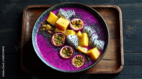 A vibrant fruit bowl featuring dragon fruit, mango, and passion fruit on a rustic wooden tray, perfect for illustrating healthy eating or tropical cuisine.