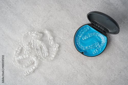 Clear dental aligner and blue case on marble table. Orthodontic mouthpiece storage.
