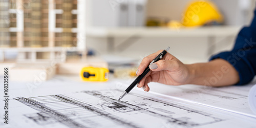 Papier peint Close up hand of Architect or engineer hand holding pen working on blueprint construction floor plans on desk with engineering tools