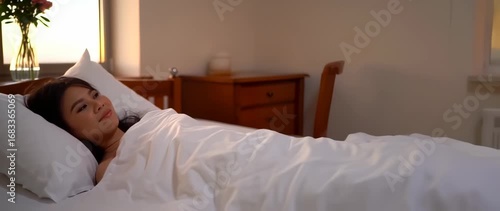 Woman lying in bed at sunrise