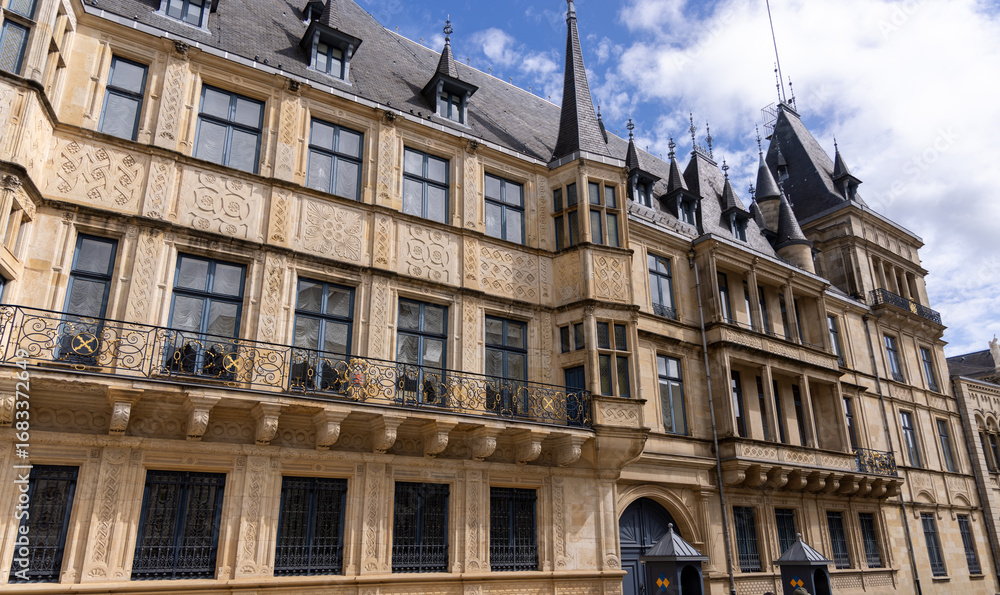 Fototapeta premium Grand Ducal Palace, official residence of the Grand Duke of Luxembourg, showcases its Renaissance architecture with detailed facade, ornate balconies, and pointed towers under a bright sky